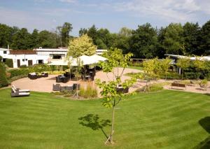 a green yard with a park with benches and an umbrella at Crowne Plaza Felbridge - Gatwick, an IHG Hotel in East Grinstead