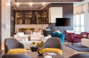 eine Lobby mit Sofas und Stühlen sowie einem TV in der Unterkunft Hilton Samarkand Regency in Samarkand