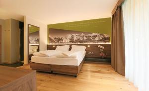 ein Schlafzimmer mit einem Bett und einem großen Wandgemälde in der Unterkunft Dolomeet Boutique Hotel in Pinzolo