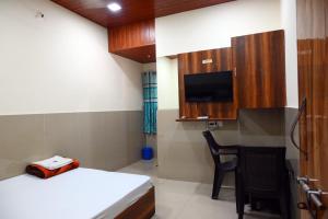 a room with a bed and a tv and a chair at P P Lodging in Pune
