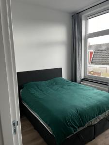 Un dormitorio con una cama verde y una ventana en Da Costa 12A en Leiden