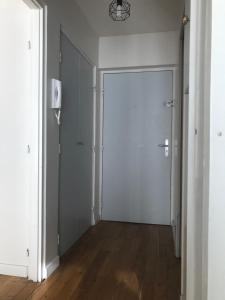 un couloir vide avec une porte blanche et du parquet. dans l'établissement Appartement Perpignan, à Perpignan