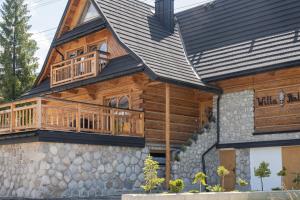 a log cabin with a deck and a porch at Willa Halna in Zakopane