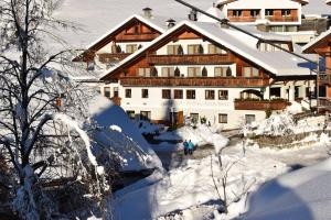 een met sneeuw bedekt gebouw waar mensen voor lopen bij Naturhotel Miraval in Perca