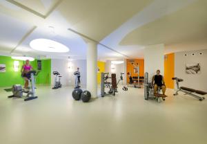 a gym with people exercising on machines in a room at Chia Laguna - Hotel Village in Chia