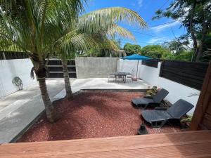 een patio met 2 stoelen, een tafel en een palmboom bij Villa Albizia 974 avec piscine et spa in Saint-Pierre