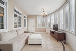 a living room with a couch and a tv and windows at Villa Laval Bord de l'eau in Laval