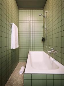 a green tiled bathroom with a tub and a towel at Max Brown Hotel Missori, part of Sircle Collection in Milan
