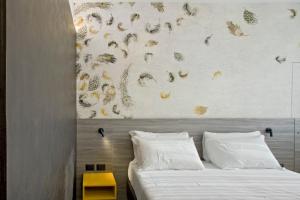 Una cama con almohadas blancas y una pared con mariposas. en Hotel Friuli en Udine