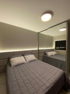 1 dormitorio con cama y espejo grande en Apartamento Av. Atlântica, com vista mar., en Balneário Camboriú