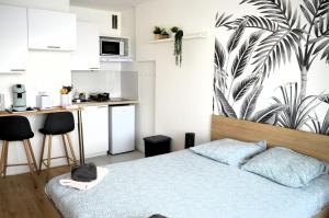 Un pequeño dormitorio con una cama y una cocina. en Le levant - avec loggia - à 20m de la plage, en Courseulles-sur-Mer