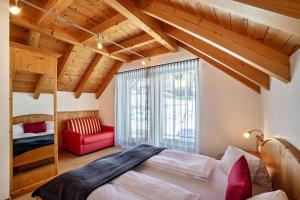 a bedroom with a bed and a red chair at Apartments Perfila Ferienchalet in Valdaora