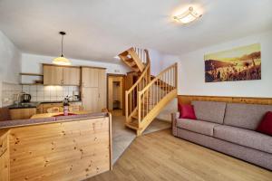a living room with a couch and a stairway at Apartments Perfila Ferienchalet in Valdaora