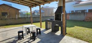 Balneário Gaivotas的住宿－casa Jardim ultramar 100mts do mar，后院的户外烧烤架,配有凳子和桌子