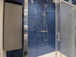 a bathroom with a shower with blue tiles at Sally in Whitstable