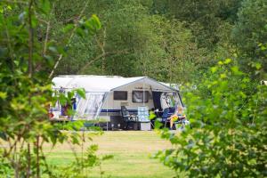 una caravana blanca estacionada en un campo con árboles en RCN Vakantiepark de Roggeberg en Appelscha
