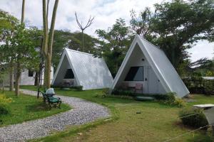 Deux petites tentes blanches avec banc dans l'herbe dans l'établissement It my life cafe x camp, à Ban Tha Sai