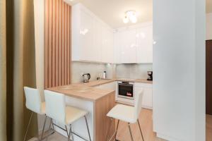 a kitchen with white chairs and a wooden counter top at Apartament Marmurowy Ku Morzu by Holidaysun in Sianozety