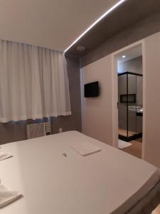 Habitación con cama blanca y TV. en Hotel Malaga (Adult Only), en Río de Janeiro