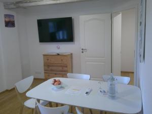 a white table with white chairs and a television on a wall at Unseburg-Ferienwohnung 3 