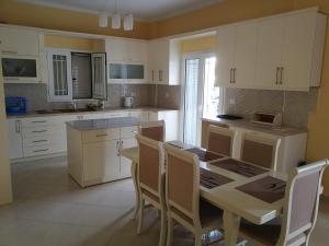 a kitchen with white cabinets and a table and chairs at Emi's Villa in Ksamil