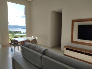 uma sala de estar com um sofá, uma televisão e uma mesa em Casa Brisas do Lago em Capitólio