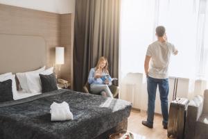 a man standing in a hotel room with a woman holding a baby at Ramada Encore Kyiv in Kyiv