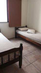 2 camas num quarto com piso em azulejo em ferratti em Guarapari