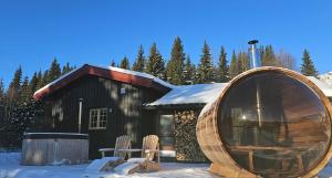 a log cabin with two chairs in the snow at Huso Mountain Lodge - Hemsedal in Eikregardane