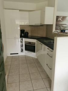 a white kitchen with white cabinets and a sink at Groot vakantiehuis direct aan het Zeeuwse strand in Kamperland