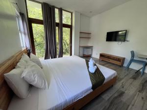 a bedroom with a large white bed and a television at Blue Lagoon Inn & Suites in Puerto Princesa City