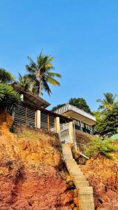 a house on top of a cliff with a palm tree at Manshore bay in Kannur