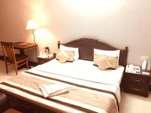 1 dormitorio con 1 cama con escritorio y lámpara en Angel NRI House en Greater Noida