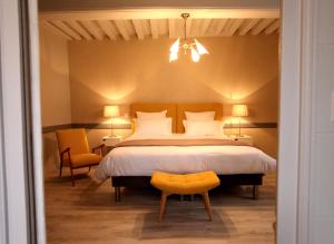 a bedroom with a large bed and a yellow chair at La Berjotine - Maison d'hôtes in Charolles