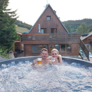 two people in a hot tub withints of beer at Horský apartmán Draps in Ostružná