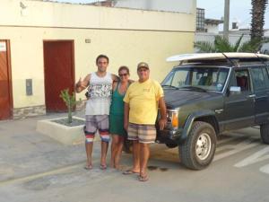 un grupo de tres personas de pie junto a un coche en Hospedaje Punta Hermosa, en Punta Hermosa