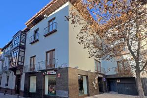 a white building with black accents next to a tree at Casual Ilbira Granada in Granada