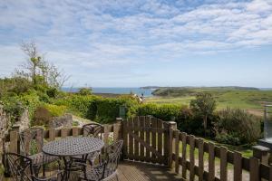 a wooden deck with a table and chairs and the ocean at Caldey Island View - Sea Views and Log Burner in Penally
