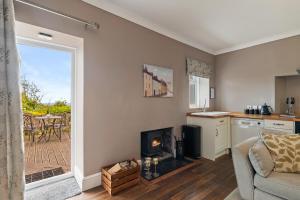 a living room with a fireplace and a kitchen with a patio at Caldey Island View - Sea Views and Log Burner in Penally