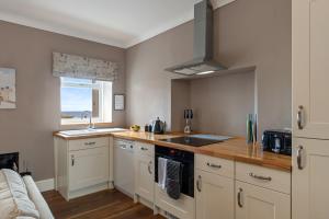 a kitchen with a sink and a stove top oven at Caldey Island View - Sea Views and Log Burner in Penally