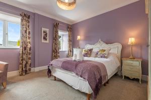 a bedroom with purple walls and a white bed at Caldey Island View - Sea Views and Log Burner in Penally
