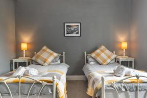 two beds in a room with two lamps on tables at Caldey Island View - Sea Views and Log Burner in Penally