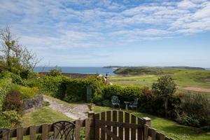 a garden with a fence and a view of the ocean at Caldey Island View - Sea Views and Log Burner in Penally