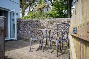 a table and chairs on a patio with a stone wall at Caldey Island View - Sea Views and Log Burner in Penally