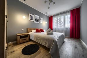 sypialnia z łóżkiem z czerwonymi zasłonami i oknem w obiekcie Central Park Red Apartment we Wrocławiu