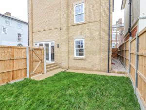 a backyard with green grass in front of a building at 21A Saville Road in Walton-on-the-Naze