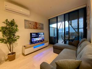 een woonkamer met een bank en een flatscreen-tv bij Peaceful & Relaxing City Escape @ Rundle Mall in Adelaide