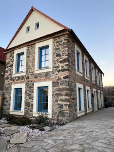 una casa de piedra con ventanas azules en una calle en ŠTAJNHAUS DUBICE 