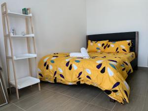 a bedroom with a bed with a yellow comforter at Lovely 2-BR service apartment with pool (melur @ troikaKB) in Kota Bharu