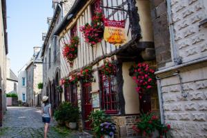 a woman walking down a street with flowers on a building at Parfum dEmbruns in Hirel